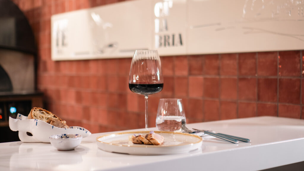 Calice di vino rosso con assaggi di cucina locale nel ristorante Chiringuito di Altafiumara Resort. I sapori e le tradizioni della Calabria: dal Mare alla Tavola