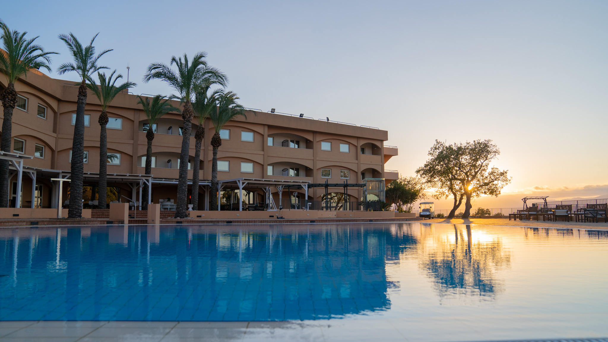 vista dell'hotel sporting all'altafiumra resrot & spa con tramonto sullo sfondo e piscina in primo piano